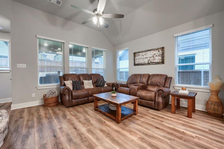 Living room featuring lofted ceiling, ceiling fan, and light hardwood / wood-style flooring