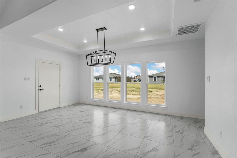 Unfurnished dining area featuring an inviting chandelier and a raised ceiling