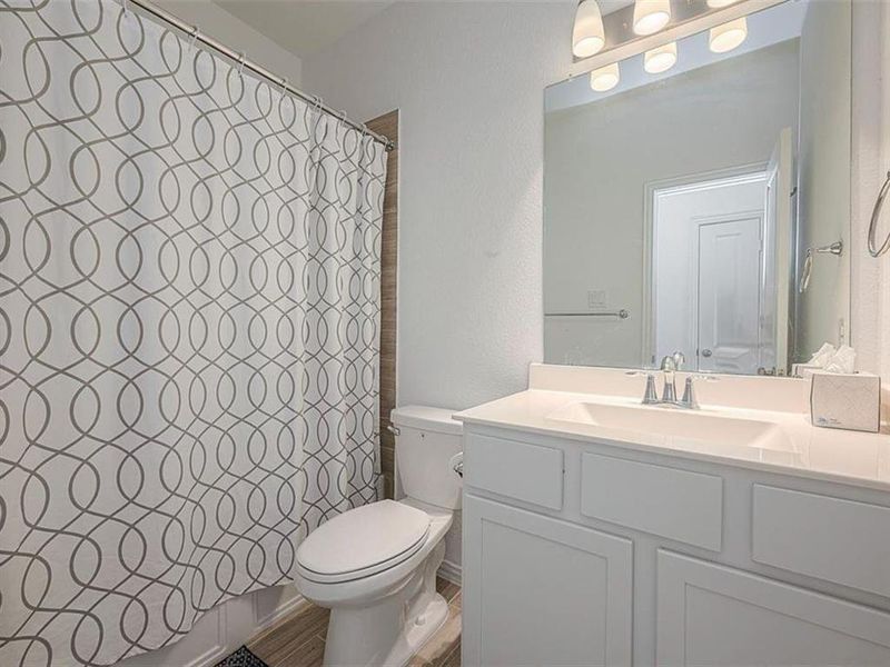 This bathroom features a toilet, sink, and mirror, providing the essentials in a clean and functional design.