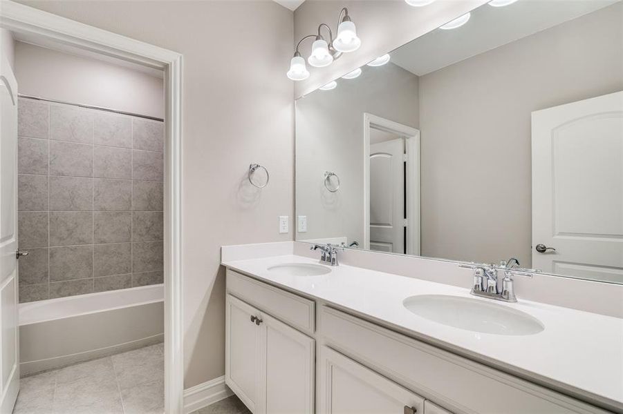 Bathroom featuring vanity, tiled shower / bath, and tile patterned floors