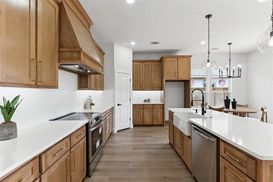 Kitchen featuring custom exhaust hood, sink, decorative light fixtures, a chandelier, and appliances with stainless steel finishes