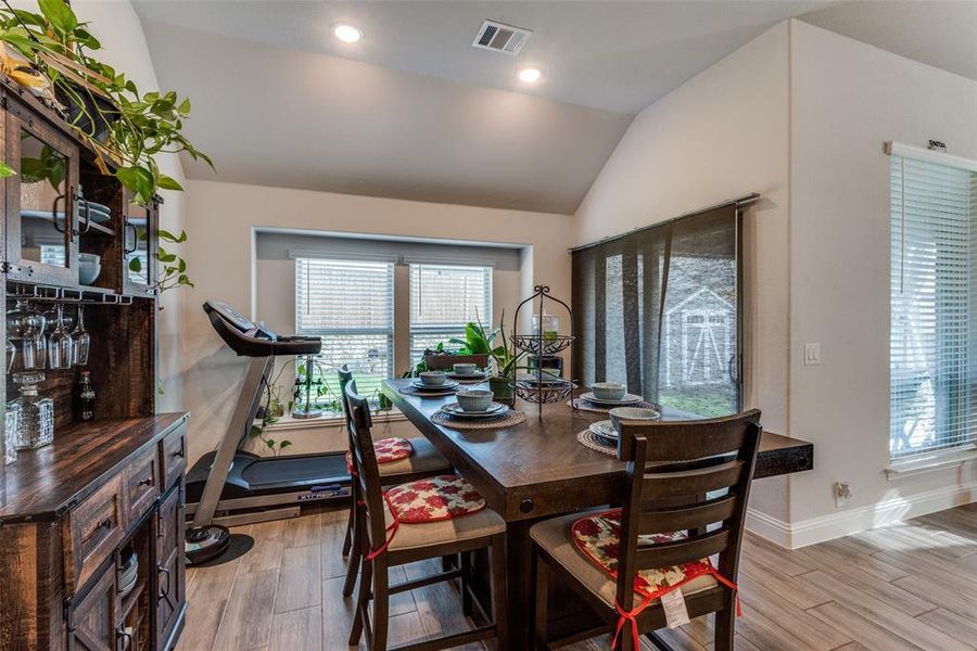 Dining area with light wood-type flooring and lofted ceiling