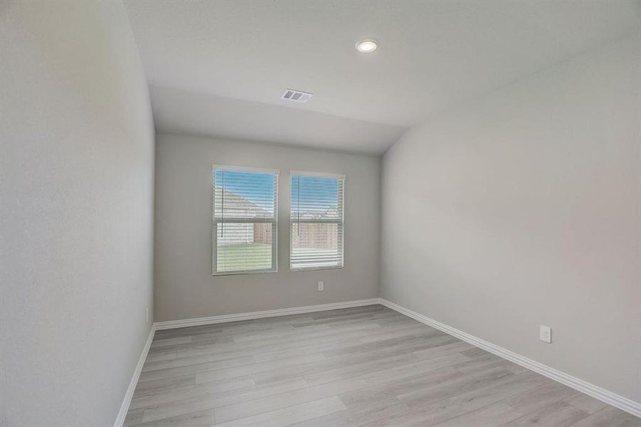 Spare room featuring light wood-type flooring and vaulted ceiling