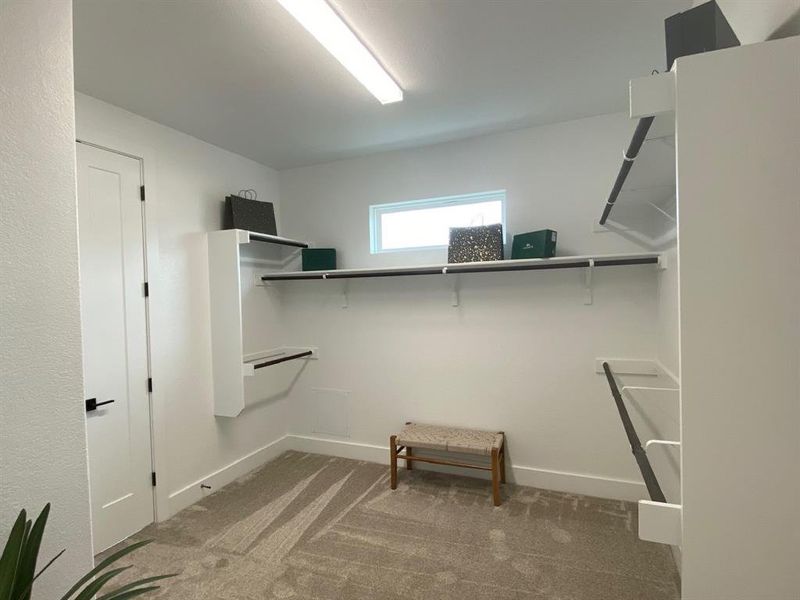 Large primary closet with door to laundry room