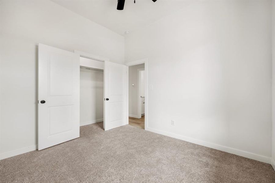 Unfurnished bedroom with a towering ceiling, light colored carpet, a closet, and ceiling fan