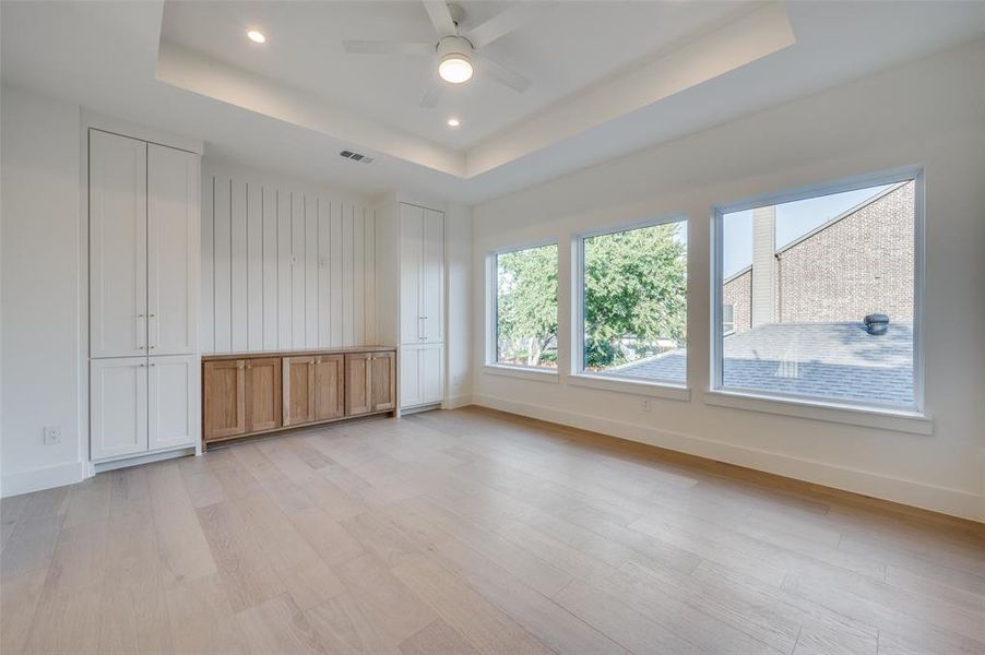 Unfurnished room with ceiling fan, a raised ceiling, and light hardwood / wood-style flooring