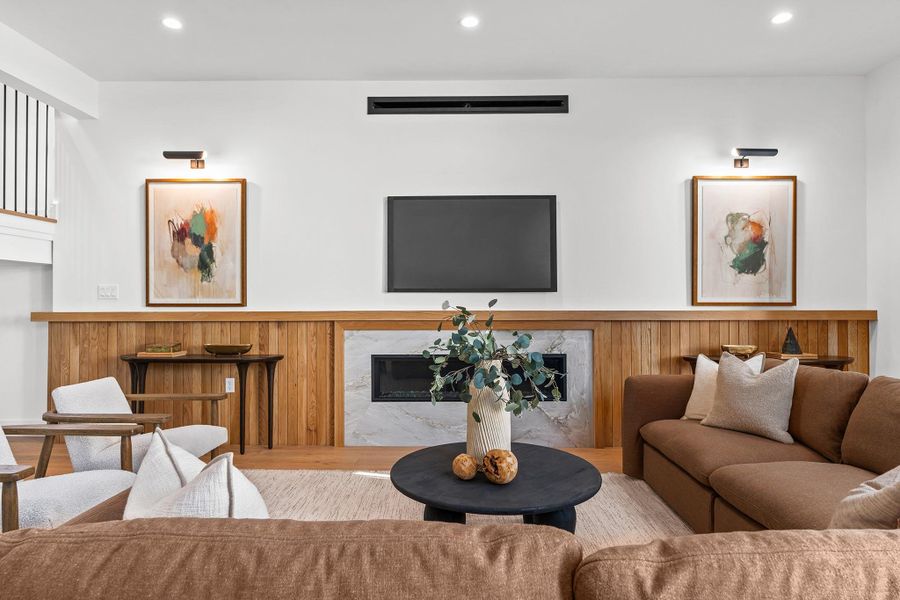 The living room is centered around a 60" linear gas fireplace set in a marble surround, complimented by an oak accent wall.