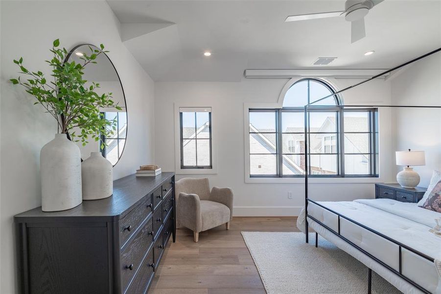 Primary bedroom featuring ceiling fan and light hardwood flooring, Pella windows, and automatic shades