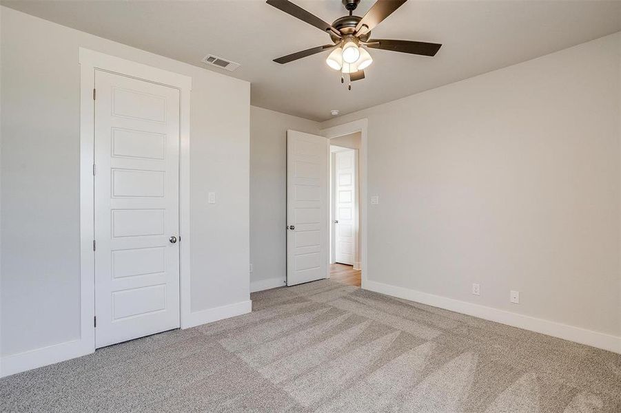 Unfurnished bedroom featuring light colored carpet and ceiling fan