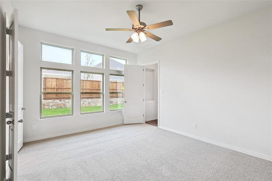 Unfurnished room with ceiling fan and light colored carpet