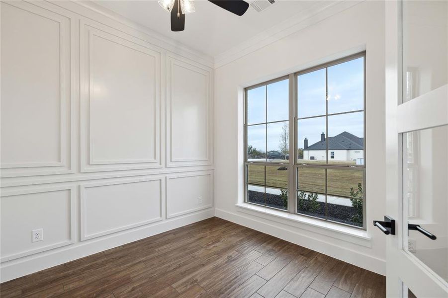 Empty room featuring ceiling fan, dark hardwood / wood-style floors, and ornamental molding