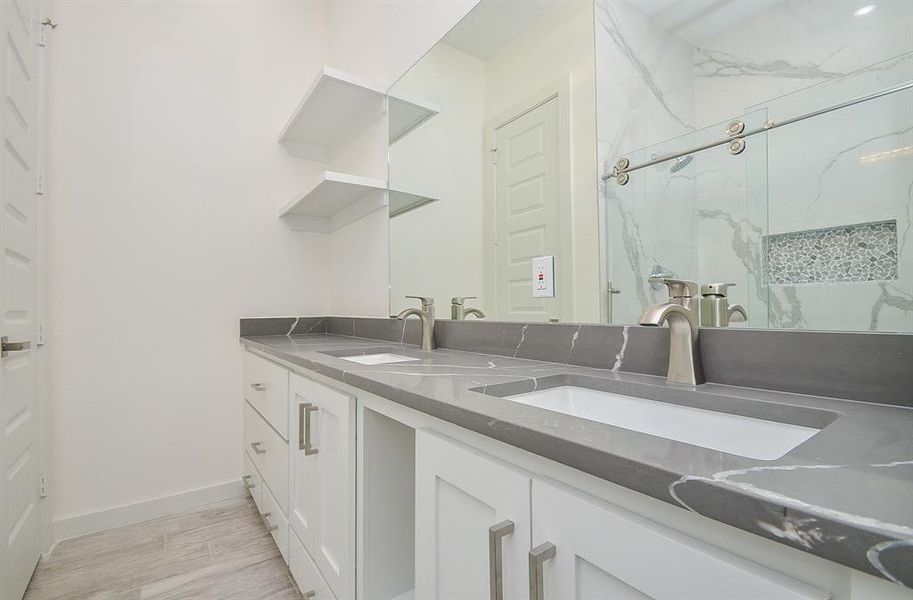 This exquisite ensuite exudes bliss with dual sinks on gleaming quartz countertop, and an oversized glass shower enclosure with porcelain tile surround. Likewise, the lush laminated floors bring an extra level of comfort into this master bath.