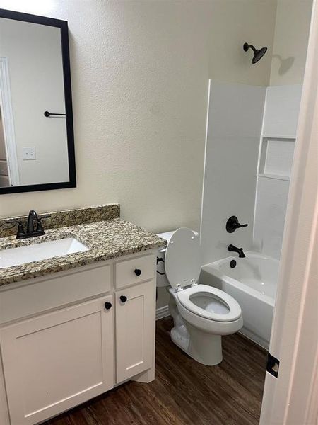Full bathroom featuring bathing tub / shower combination, toilet, vanity, and hardwood / wood-style floors