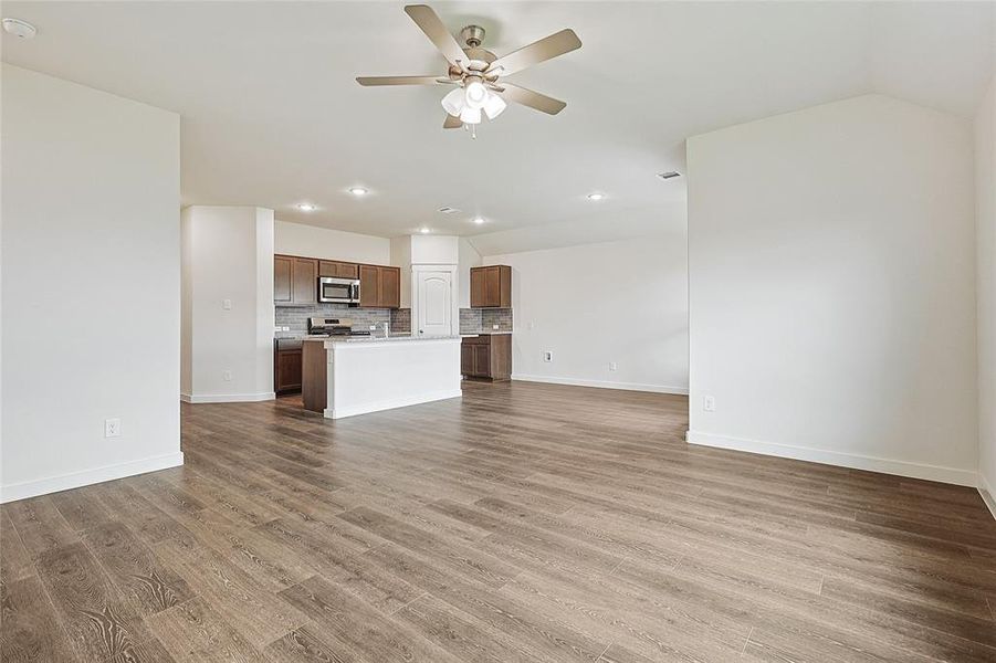 Unfurnished living room featuring wood-type flooring and ceiling fan