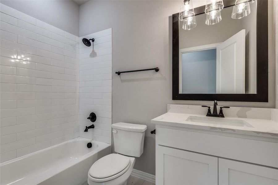 Full bathroom featuring toilet, tiled shower / bath combo, and vanity