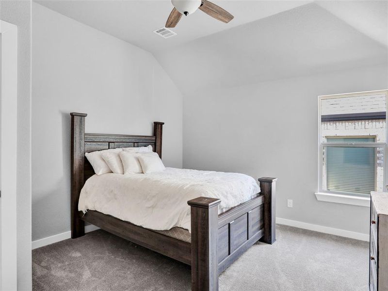 Upstairs bedroom with ceiling fan and vaulted ceiling