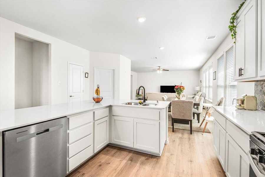 Kitchen featuring white cabinets, stainless steel appliances, light wood-type flooring, and sink