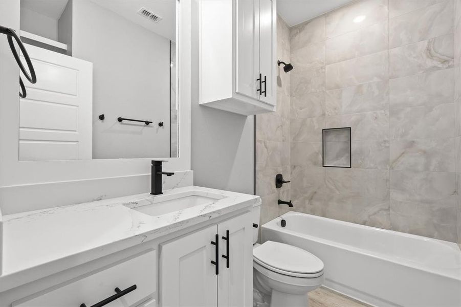 Full bathroom featuring tiled shower / bath combo, vanity, toilet, and wood-type flooring