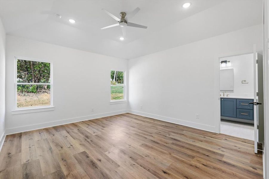 Unfurnished bedroom featuring luxury vinyl flooring, lofted ceiling, ceiling fan, and ensuite bathroom