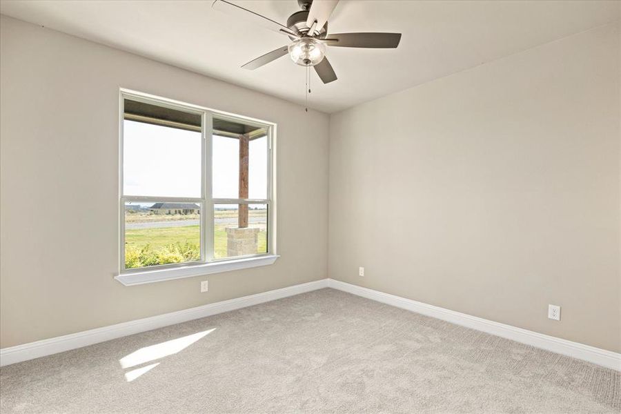 Carpeted spare room featuring ceiling fan