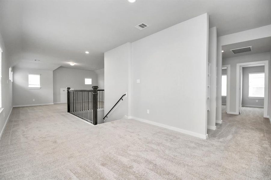 Ascend to relaxation in this fantastic loft and game room area! Ideal for both casual gatherings and adult gaming, it boasts plush carpet, lofty ceilings, custom paint, and ample windows for abundant natural light.