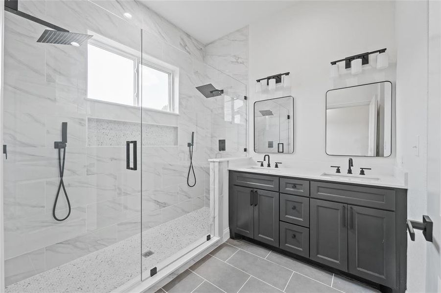 Bathroom featuring a shower with shower door, dual bowl vanity, and tile floors