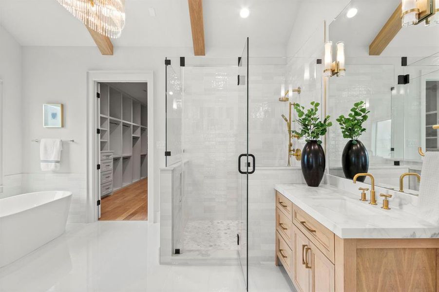 Primary Bathroom features a large glass encased walk-in shower, separate soak tub, dual vanities, arched ceilings w/ beam detail & custom built linen cabinetry.