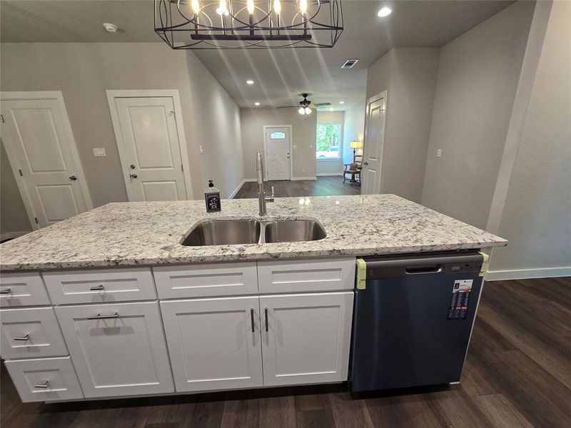 Kitchen with white cabinets, ceiling fan with notable chandelier, dishwasher, pendant lighting, and sink