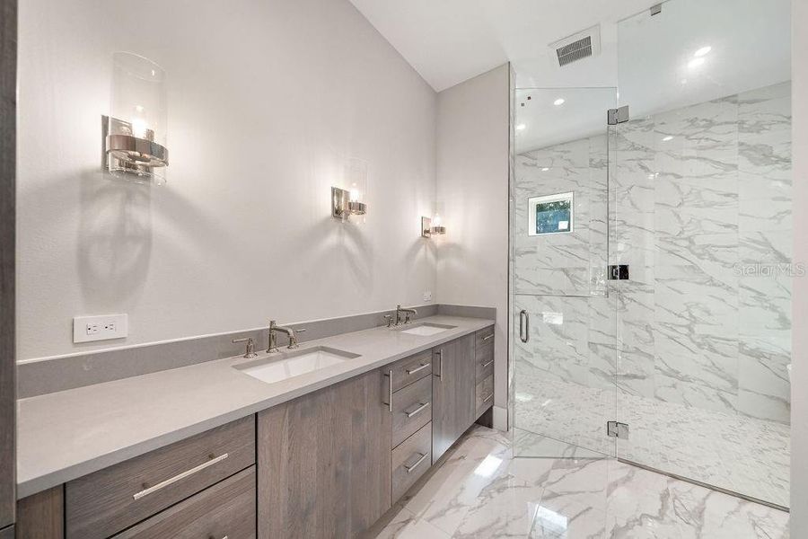 Primary bathroom with custom cabinetry and granite counters