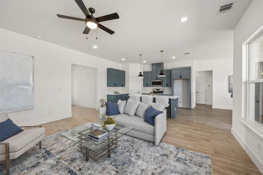 Living room with ceiling fan and light hardwood / wood-style floors