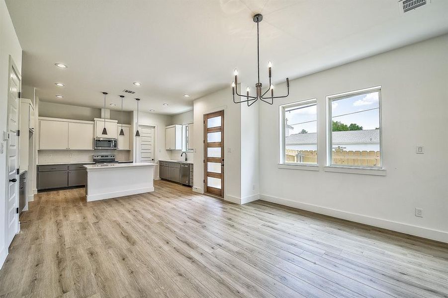 Kitchen with decorative light fixtures, a center island, stainless steel appliances, and white cabinetry