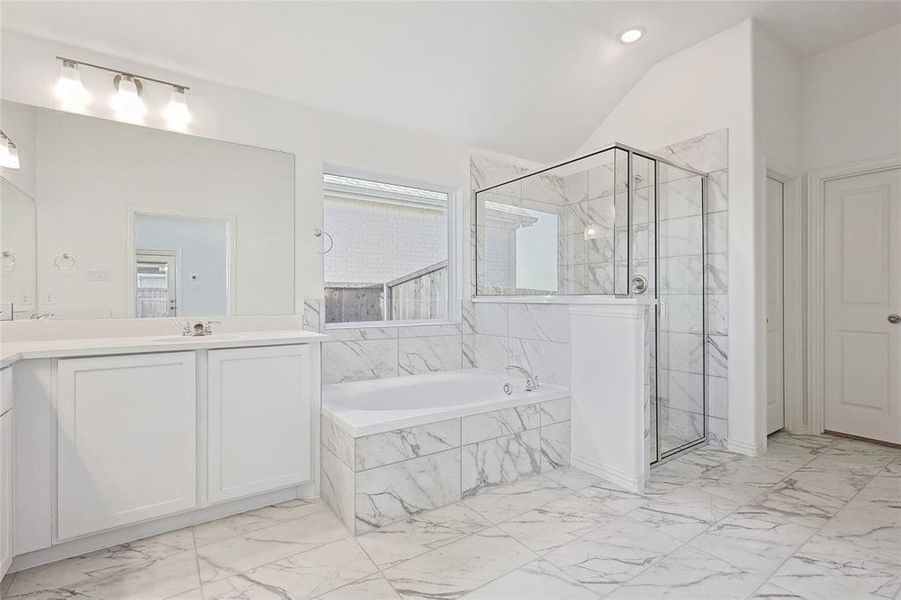 Bathroom featuring shower with separate bathtub, vaulted ceiling, and vanity