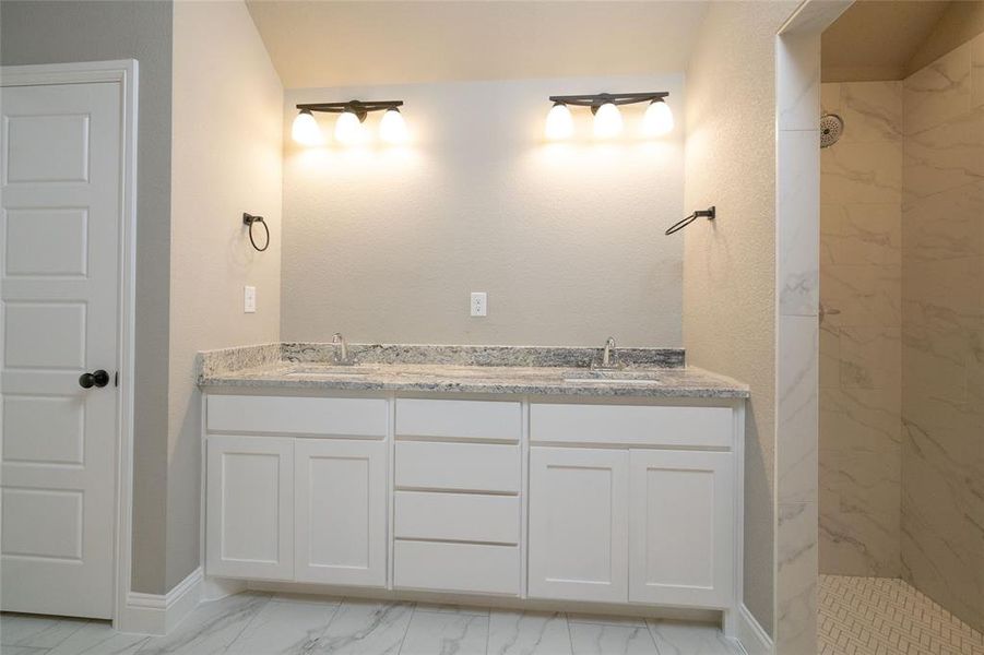 Bathroom with dual vanity, tiled shower, and tile patterned floors