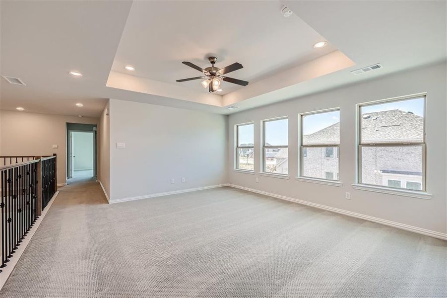 Carpeted empty room with ceiling fan and a tray ceiling