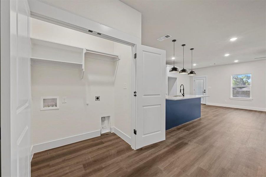 Clothes washing area featuring hookup for a washing machine, dark hardwood / wood-style flooring, electric dryer hookup, and sink