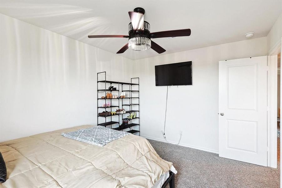 Carpeted bedroom featuring ceiling fan