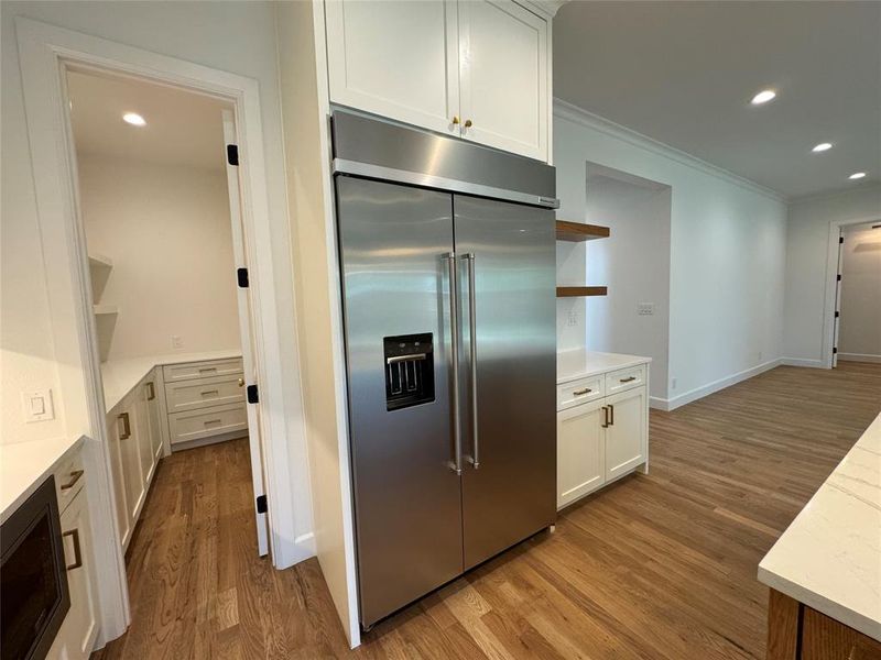 Kitchen with white cabinetry, light hardwood / wood-style flooring, and built in fridge