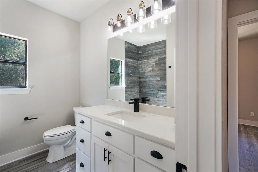 Bathroom featuring tiled shower, vanity, toilet, and hardwood / wood-style floors