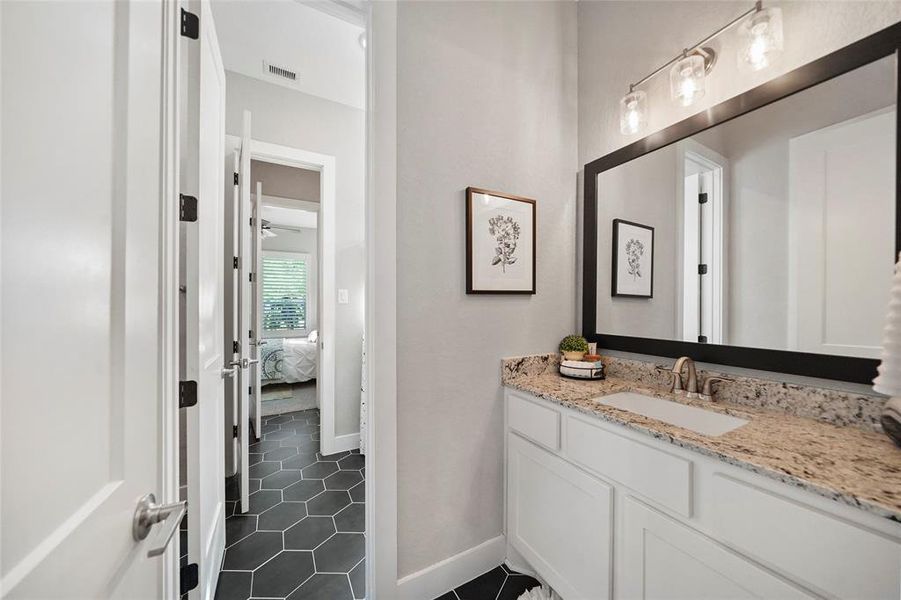 Twin dressing areas provide two guest suites with a private vanity. Each vanity offers a granite countertop and a framed mirror with upgraded vanity lights above.