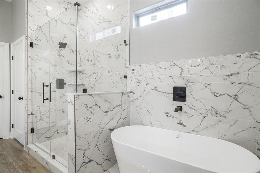 Bathroom with hardwood / wood-style flooring, shower with separate bathtub, and tile walls