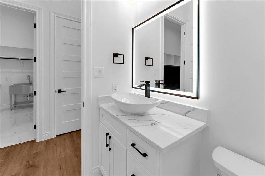 Powder room located at the front of the house with ceramic vessel sink, quartz countertop, matte black hardware and storage.