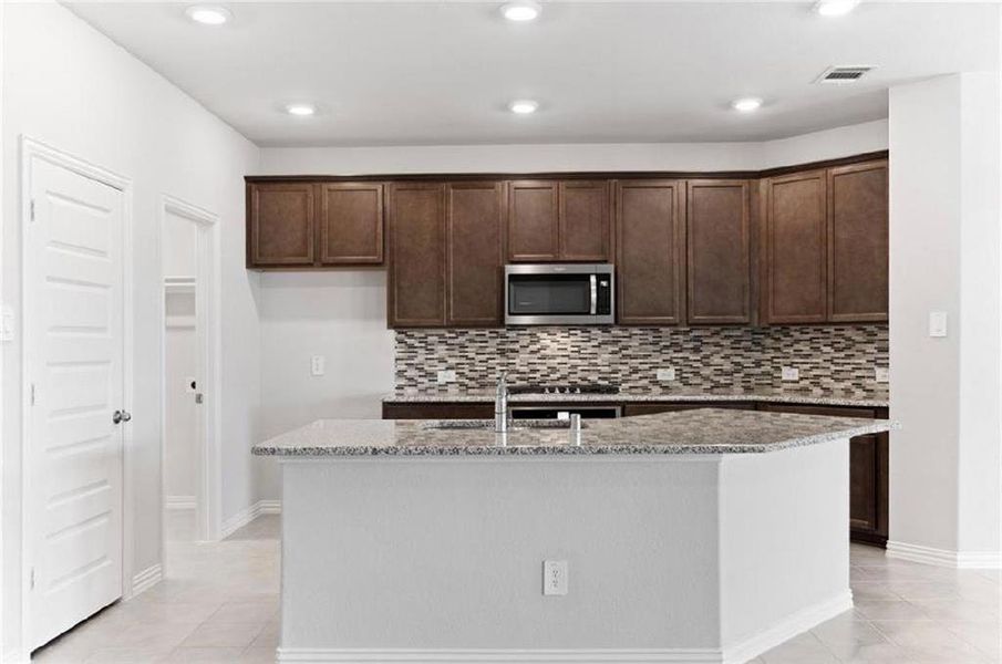 Kitchen featuring 42 Inch Cabinetry, Granite Countertop and island with sink, and eat in bar area