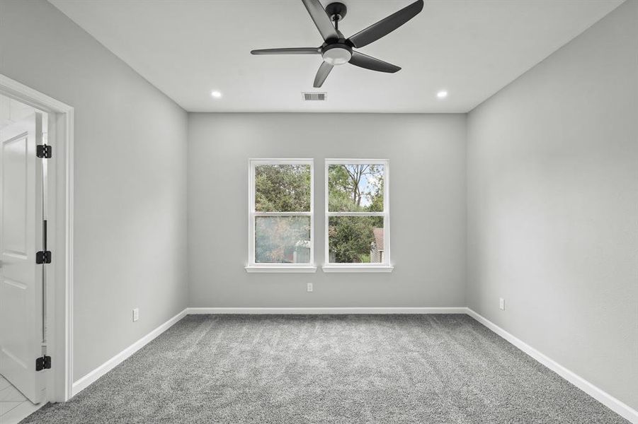 Secondary bedroom with plush carpet and ceiling fan.