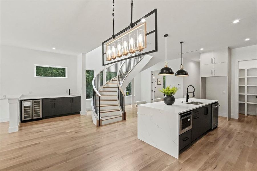 Kitchen with white cabinetry, light wood-type flooring, sink, and pendant lighting