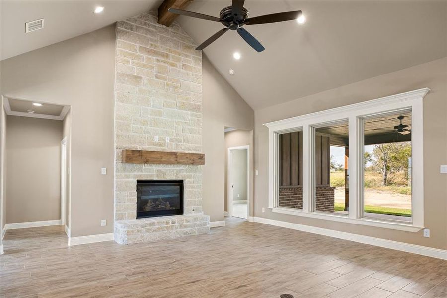 Unfurnished living room featuring beam ceiling, high vaulted ceiling, and light wood-type flooring