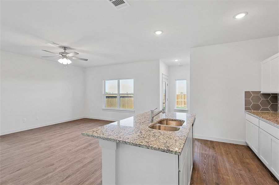 Kitchen with ceiling fan, sink, a center island with sink, white cabinetry, and hardwood / wood-style flooring