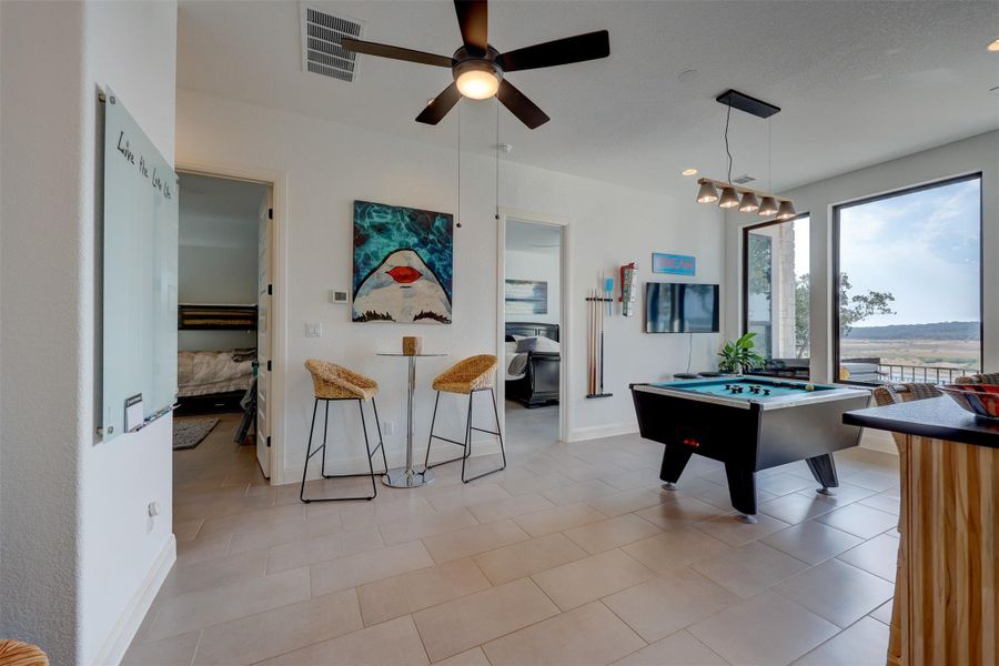 Game Room or Possible Formal Dining Room with 3 large picture Windows and Door to Covered Patio. Glass Dry Erase Board, Fan & Custom Lighting. Bumper Pool Table Can Convey!