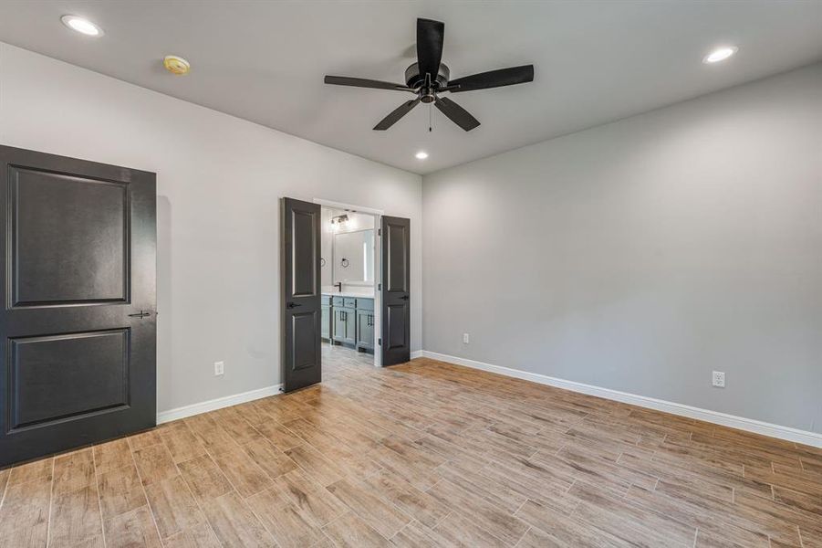 Unfurnished bedroom with ensuite bath, light hardwood / wood-style flooring, and ceiling fan