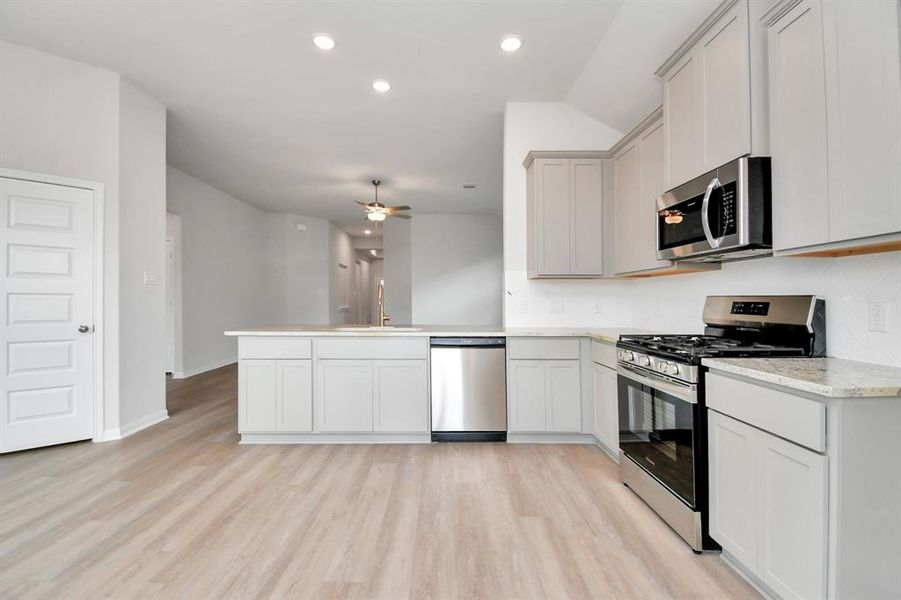 The space is bright and welcoming, with light-colored cabinetry and sleek countertops that provide a fresh, clean look. Stainless steel appliances, including a built-in microwave and gas range, offer both style and functionality.