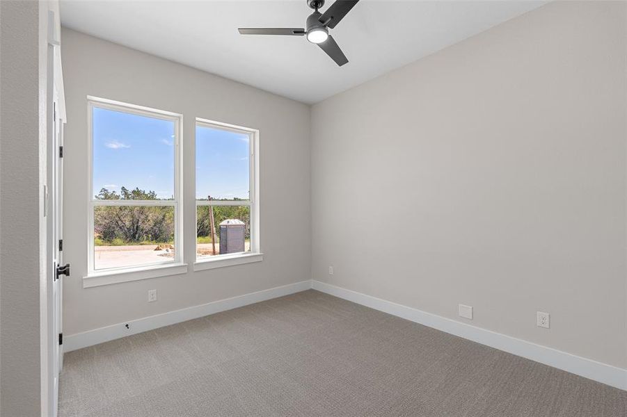 Empty room with ceiling fan and light carpet